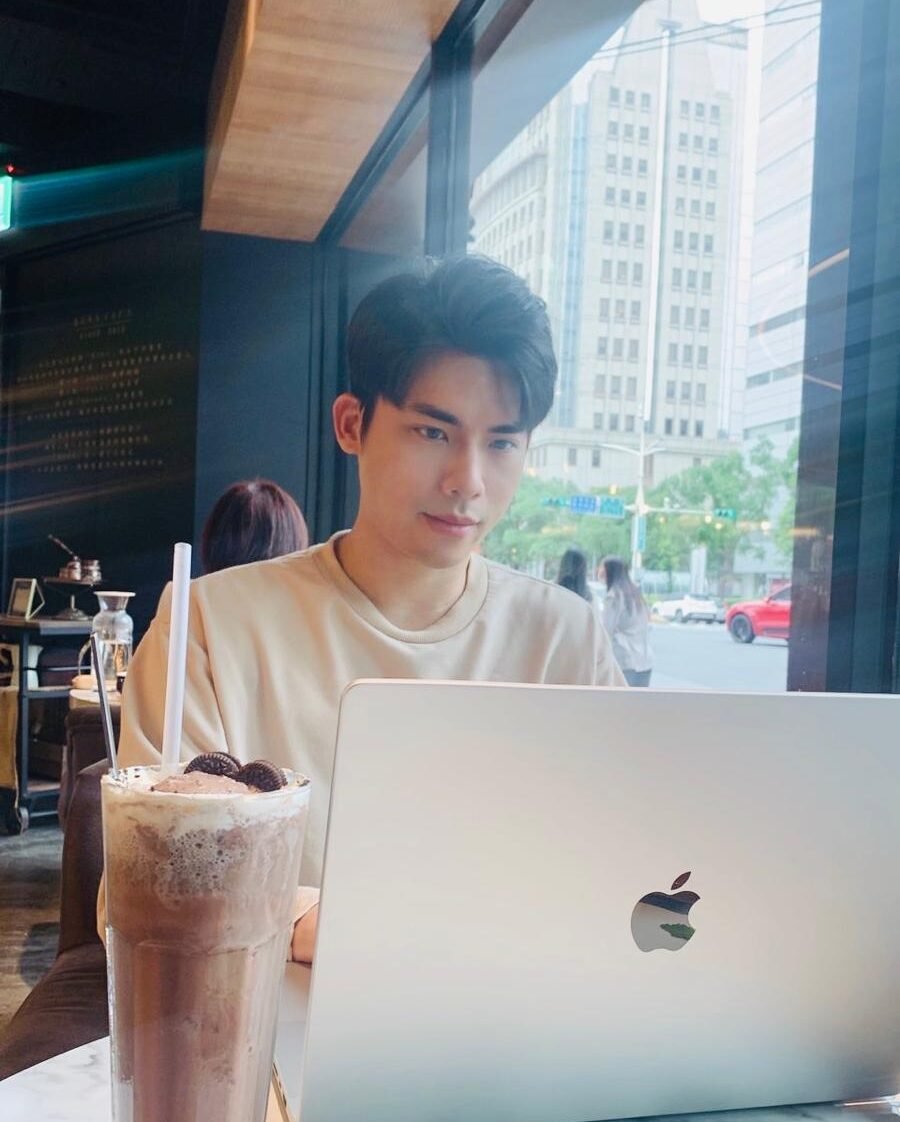 Portrait of Chris Chen working on a laptop in a cozy cafe, illustrating a creative and focused work environment.